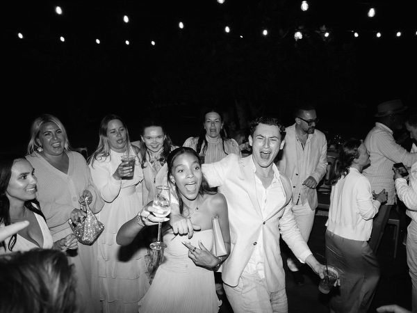 Black and white photo of friends celebrating together on the crowded wedding dance floor