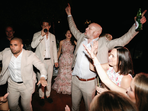 Wedding guest dancing with raised arms during the late-night celebration in Aegina