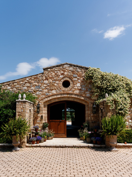 Stone entrance of Pyrgos Petreza beneath a bright blue sky near Athens