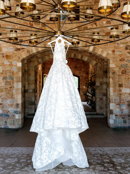 Lace wedding gown hanging beneath chandeliers inside Pyrgos Petreza