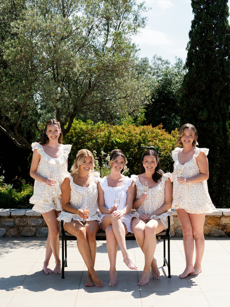 Bride and bridesmaids seated together outdoors during relaxed morning preparations