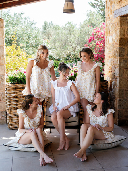 Bride and bridesmaids gathered together on outdoor steps at the venue