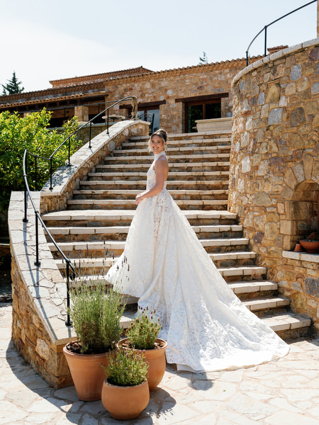 Bride in her lace wedding gown standing on the stone staircase at Pyrgos Petreza
