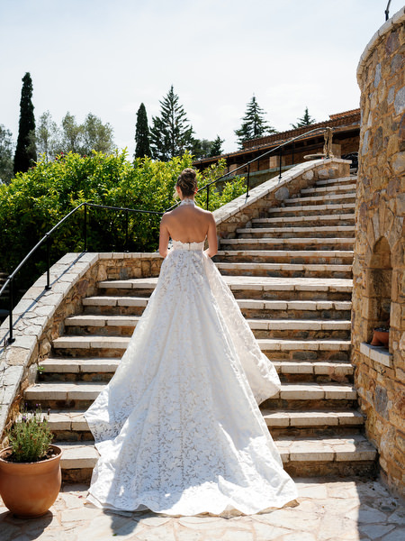 Bride showing the long train of her lace wedding gown on the venue staircase