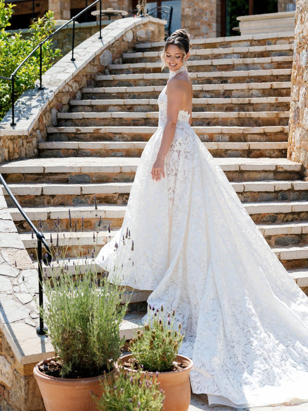 Bride posing on the stone staircase with her lace gown and veil flowing behind her