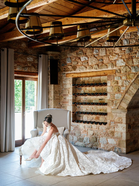 Bride seated beneath chandeliers inside the stone interior of Pyrgos Petreza