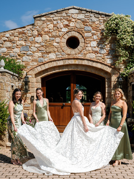 Bride and bridesmaids posing outside the stone entrance of Pyrgos Petreza