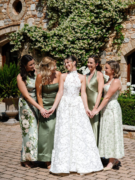 Bride surrounded by bridesmaids in soft green dresses during wedding portraits