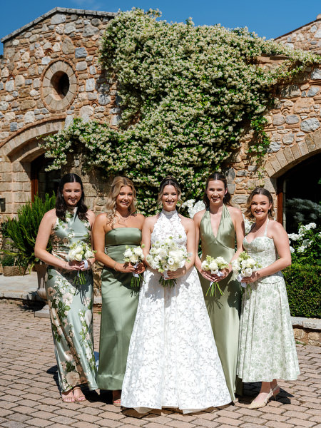 Bridal party portrait outside the ivy-covered stone architecture of Pyrgos Petreza
