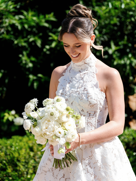 Bride holding a white floral bouquet in her lace wedding gown
