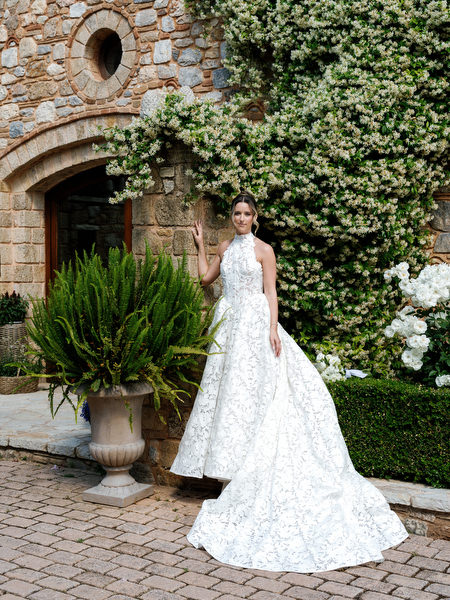 Full-length bridal portrait outside the ivy-covered stone entrance of Pyrgos Petreza
