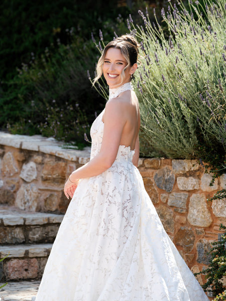 Bride looking back over her shoulder in her lace wedding gown near the stone walls