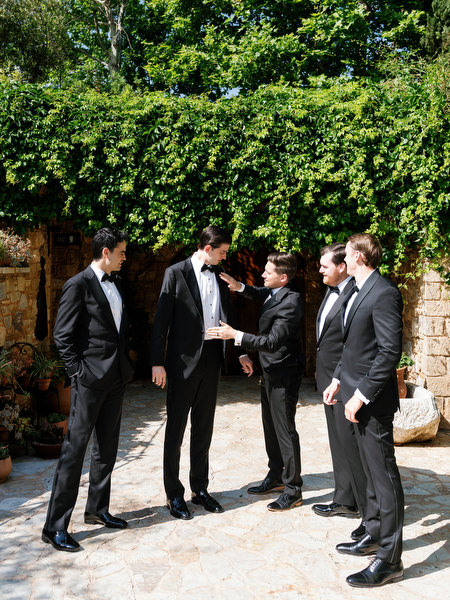 Groom and groomsmen posing together in classic black tuxedos before the ceremony