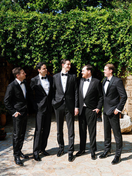 Groomsmen standing together beneath greenery during wedding portraits near Athens