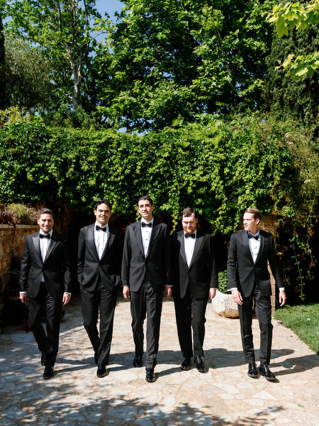 Groom and groomsmen walking together through the estate before the ceremony