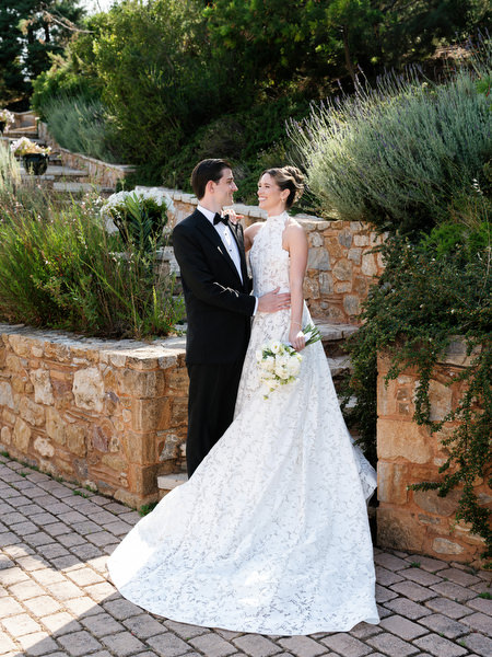 Groom adjusting his bow tie as the bride smiles beside him at Pyrgos Petreza