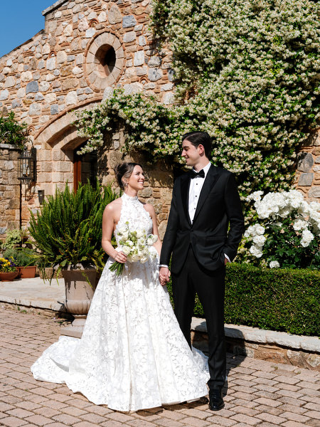 Bride and groom standing together in front of the ivy-covered stone entrance