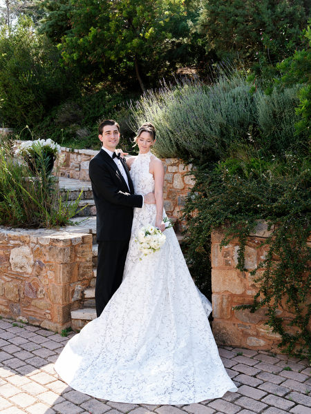 Newlyweds standing together in the gardens with stone walls and Mediterranean plants