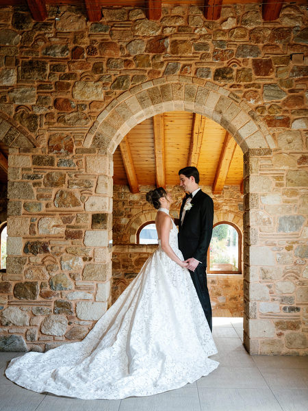 Bride and groom posing beneath a stone arch inside Pyrgos Petreza
