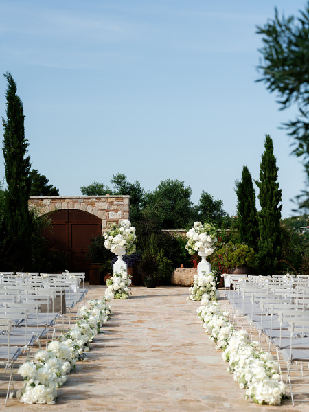 Elegant outdoor wedding aisle lined with white flowers at Pyrgos Petreza