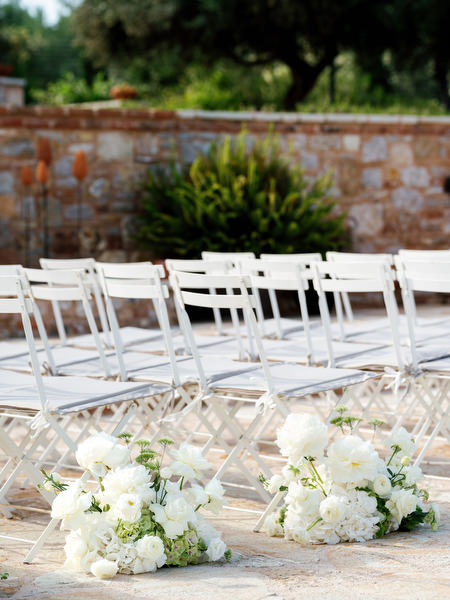Close-up of white floral aisle arrangements and ceremony chairs at Pyrgos Petreza