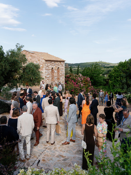 Wedding guests standing together beneath the Greek summer sky before the ceremony