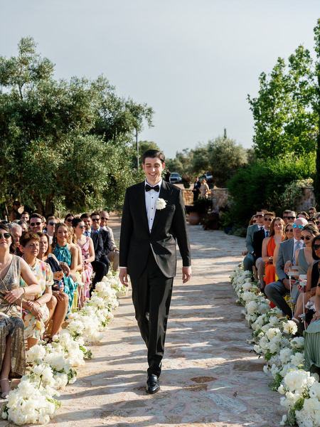 Groom walking down the flower-lined aisle at his Pyrgos Petreza wedding