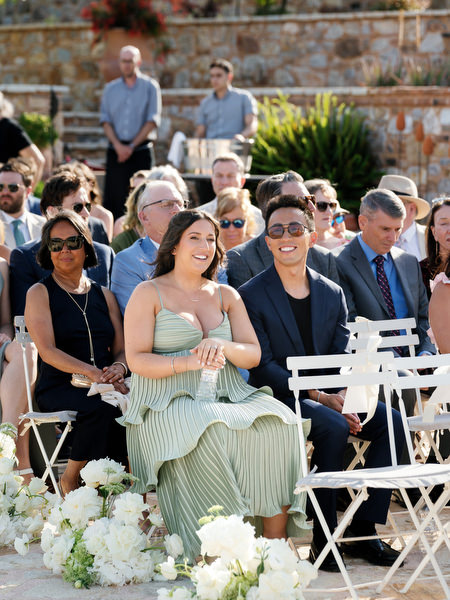 Bridesmaids seated together with white bouquets during the Pyrgos Petreza ceremony
