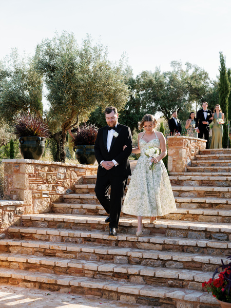 Groomsman and Bridesmaid walking down the stone steps toward the outdoor wedding ceremony