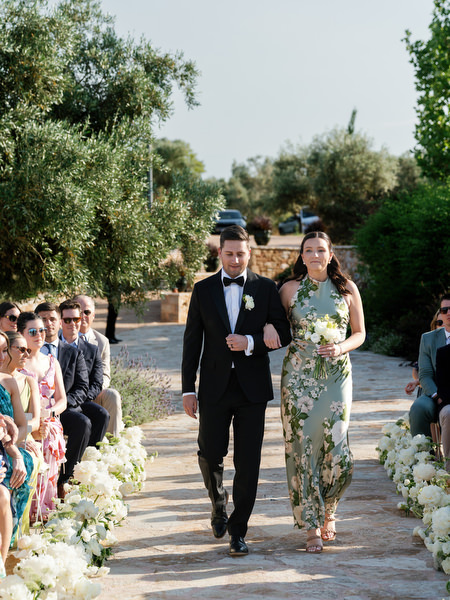 Wedding party walking down the flower-lined ceremony aisle