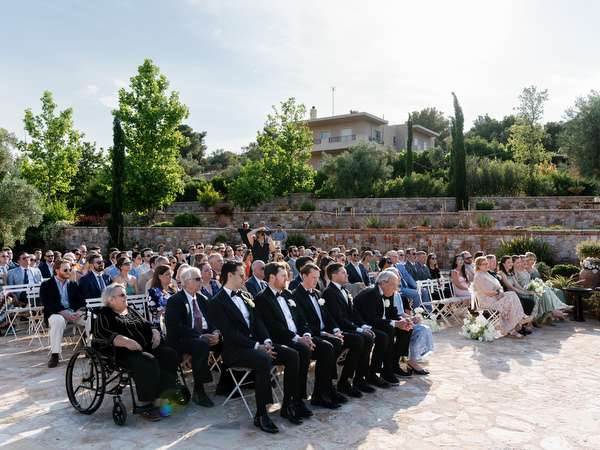 Wedding guests seated in the stone courtyard during the destination ceremony