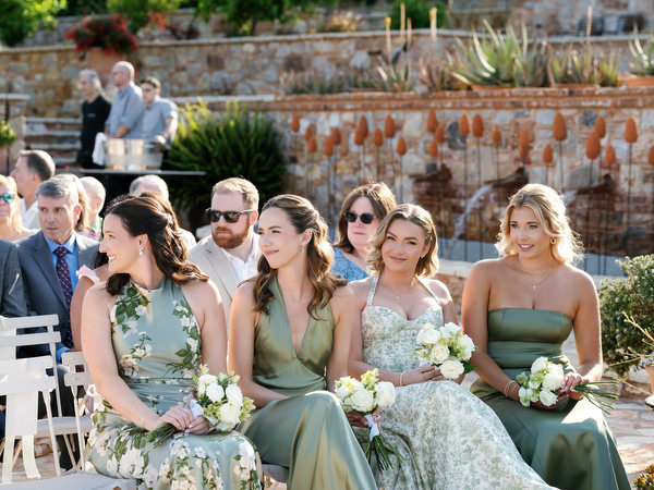 Bridesmaids watching the ceremony while holding white floral bouquets