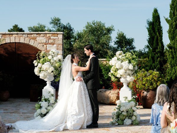 Bride and groom sharing a kiss at the flower-lined altar during their Pyrgos Petreza ceremony