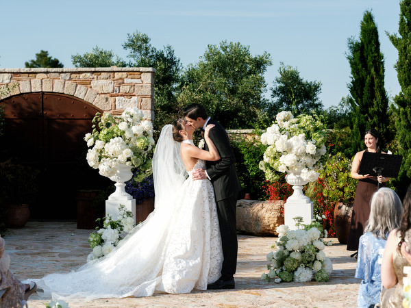 Newlyweds kissing beneath the open Greek sky after exchanging vows near Athens