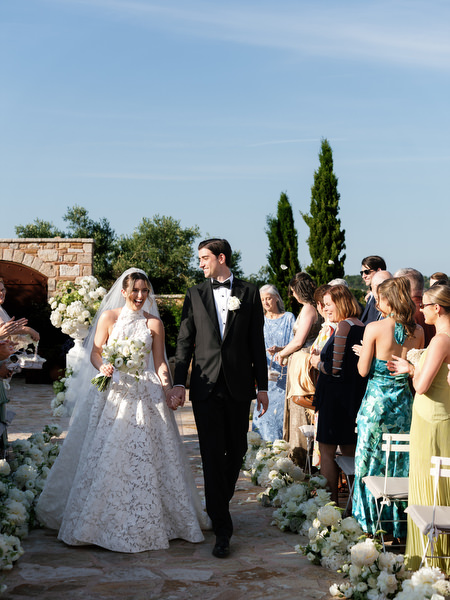 Newlyweds walking hand in hand through the flower-lined aisle after the ceremony