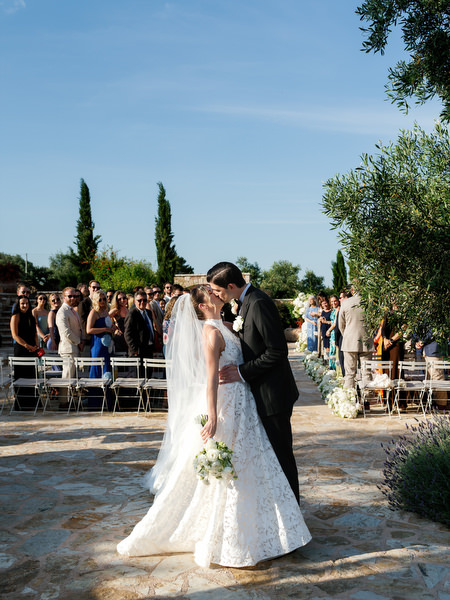Bride and groom sharing a joyful kiss as guests celebrate around them