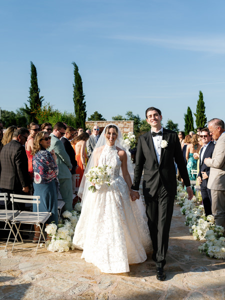 Newlyweds walking together through the courtyard after their Pyrgos Petreza ceremony