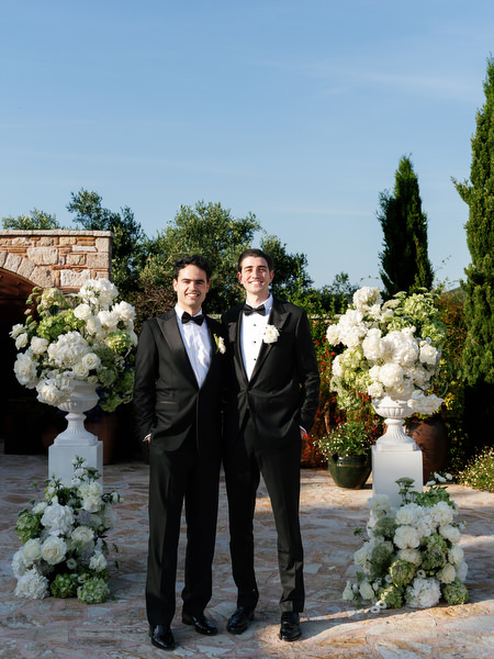 Groom posing with family members beside the floral wedding ceremony setup