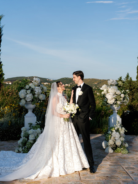 Bride and groom embracing beside white floral arrangements after the ceremony
