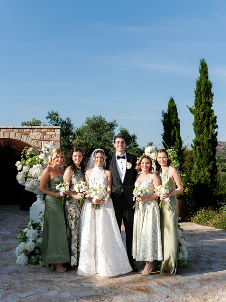 Bride, groom and bridesmaids posing together at the elegant outdoor wedding altar