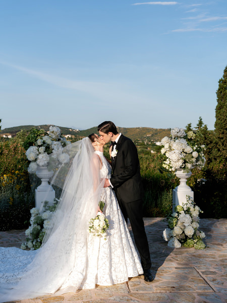 Newlyweds kissing beside the white floral ceremony arrangement at Pyrgos Petreza