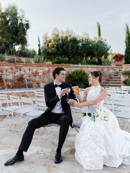 Bride and groom relaxing together on white ceremony chairs after the wedding