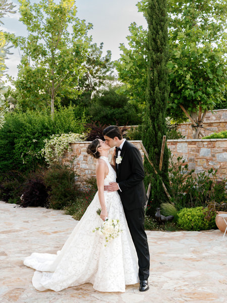 Bride and groom embracing among trees and Mediterranean greenery near Athens
