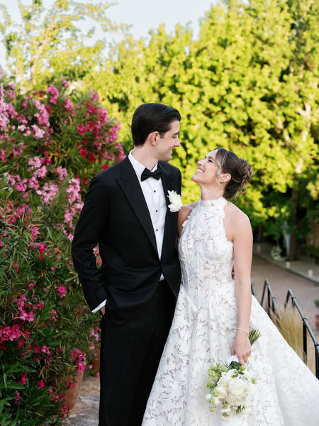 Bride and groom posing together beside vibrant bougainvillea at Pyrgos Petreza