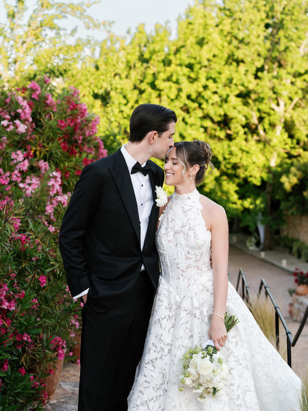 Bride and groom standing beneath colorful flowers during their Athens wedding portraits