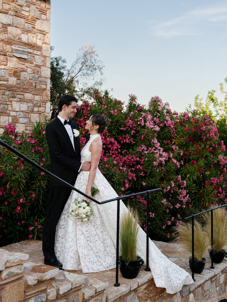 Newlyweds walking along a stone path through the gardens of Pyrgos Petreza