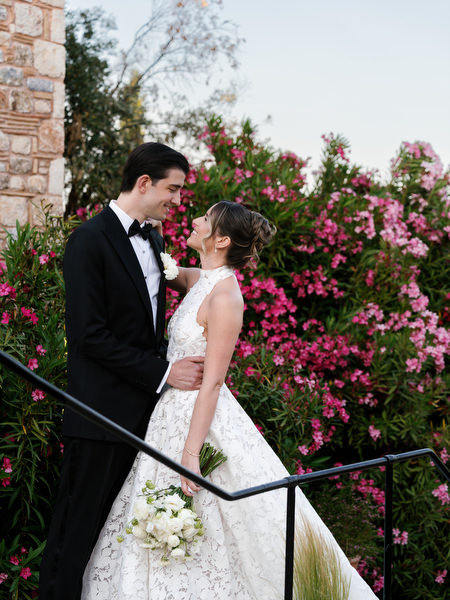 Romantic wedding portrait beside flowering bougainvillea and rustic stone architecture