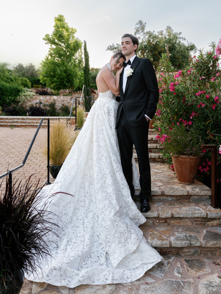 Bride and groom posing on stone steps surrounded by lush gardens at Pyrgos Petreza