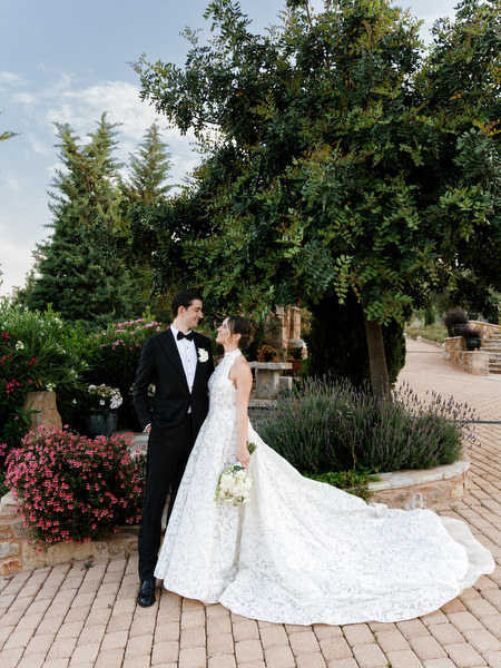 Newlyweds standing together beneath trees during golden-hour wedding portraits
