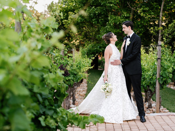 Bride and groom standing among vineyard greenery during their Pyrgos Petreza wedding